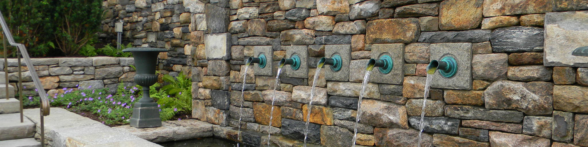 Decoarative fountain with bronze spouts on stone wall
