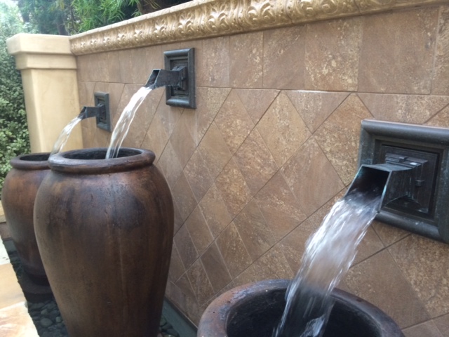 fountain spout projecting water into mouth of pot