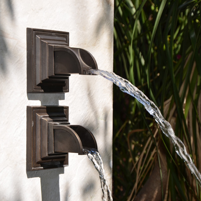 Two version of the same bronze spout each projecting a stream of water differently