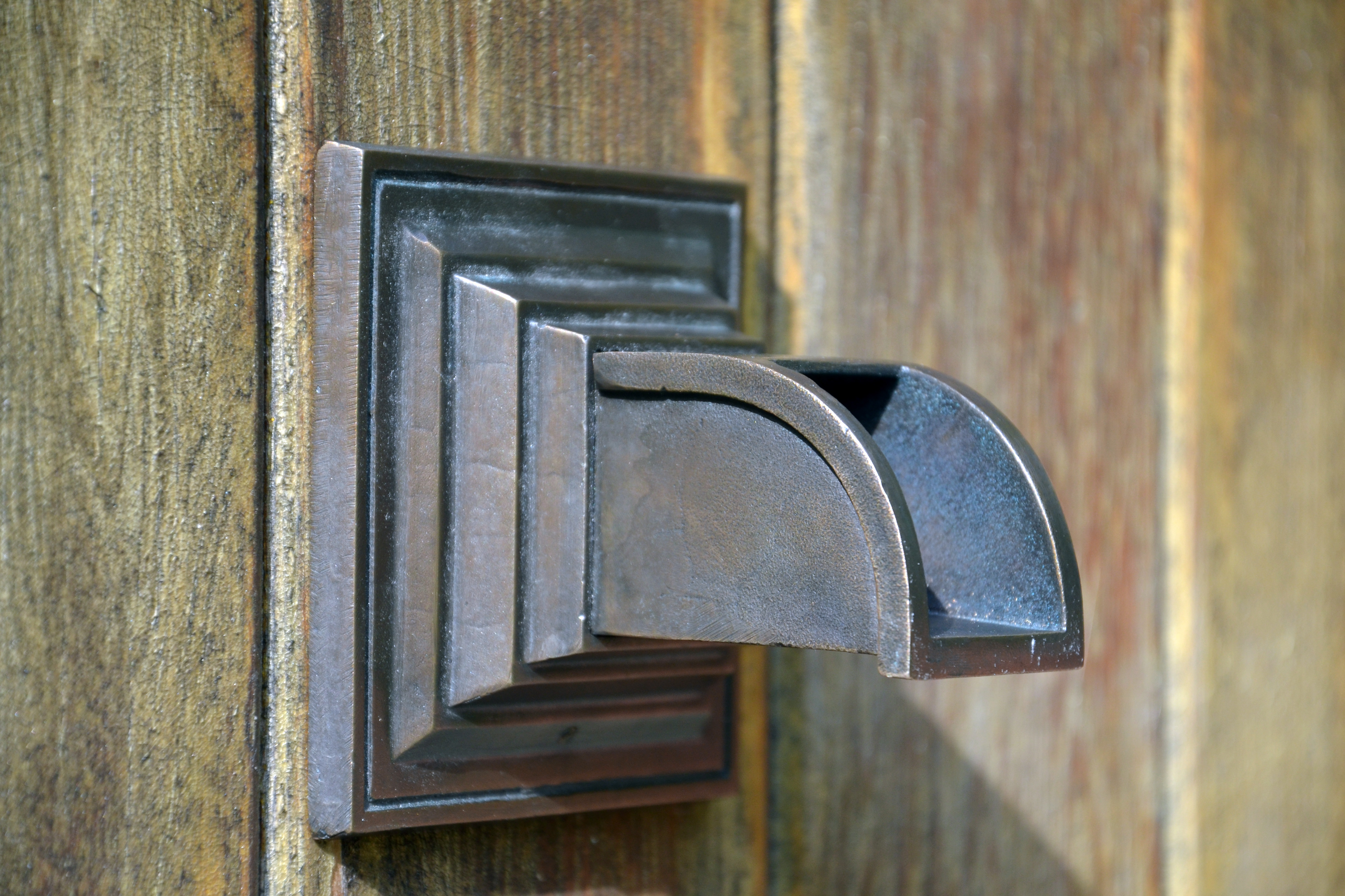 bronze fountain spout on a weathered wood background