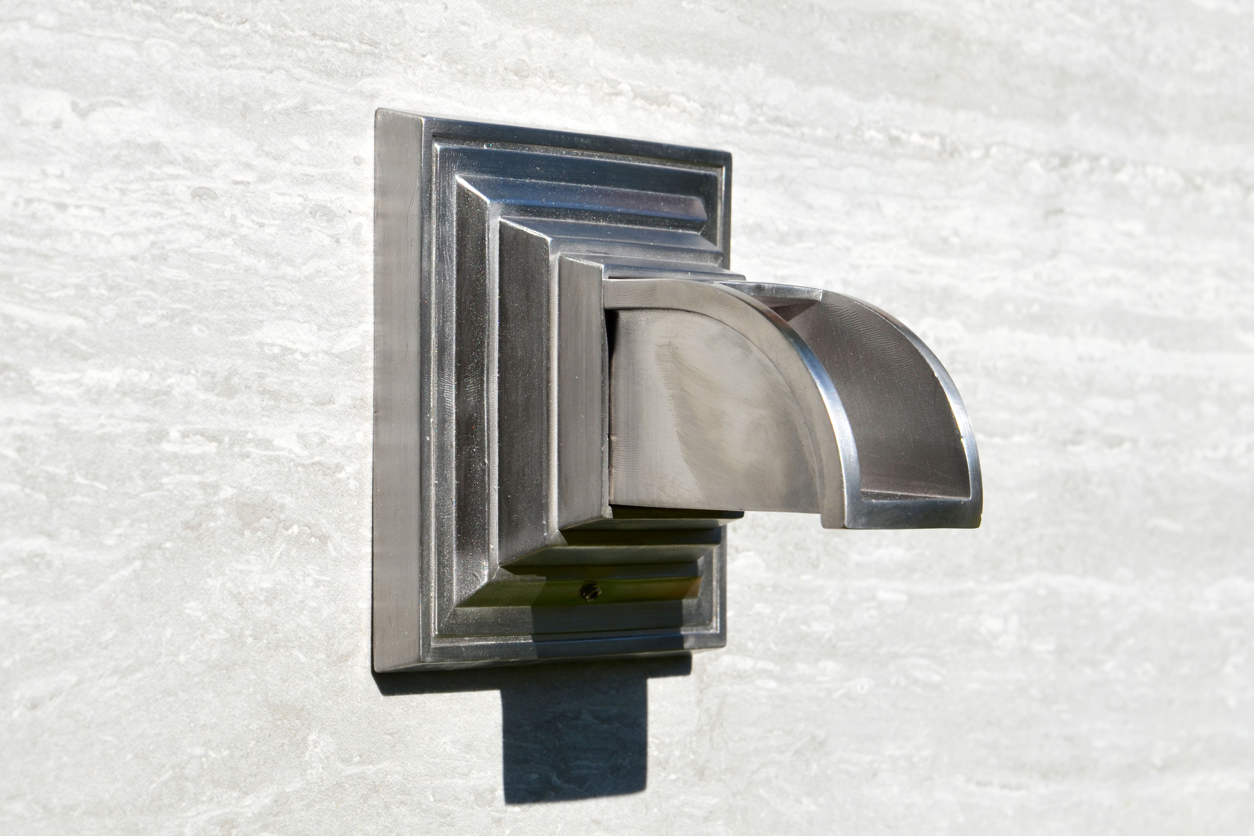 stainless steel fountain spout on a tile background