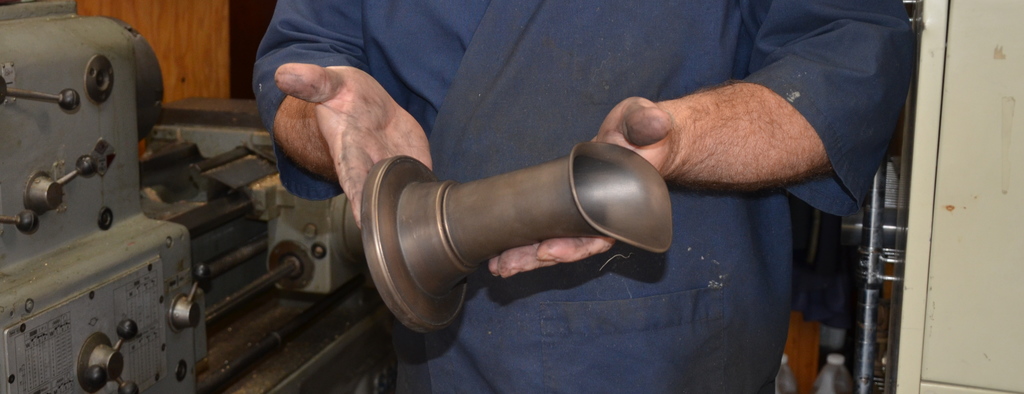 machinist holding Oona spout with metal working machinery in background